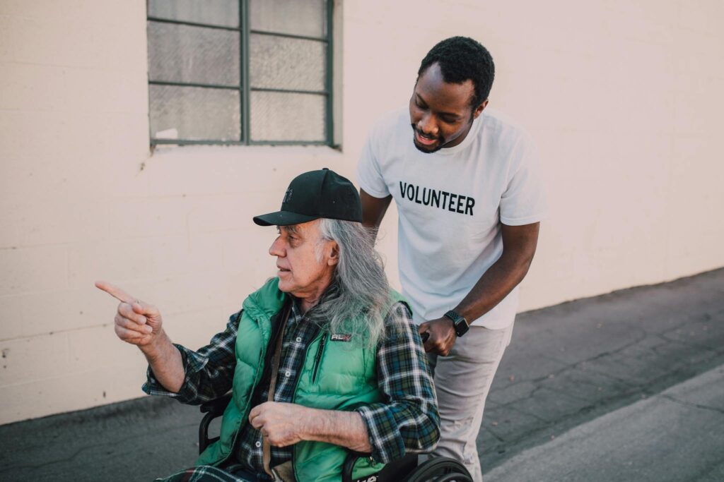 Man in White Crew Neck T-shirt and Black Hat Sitting on Concrete Bench